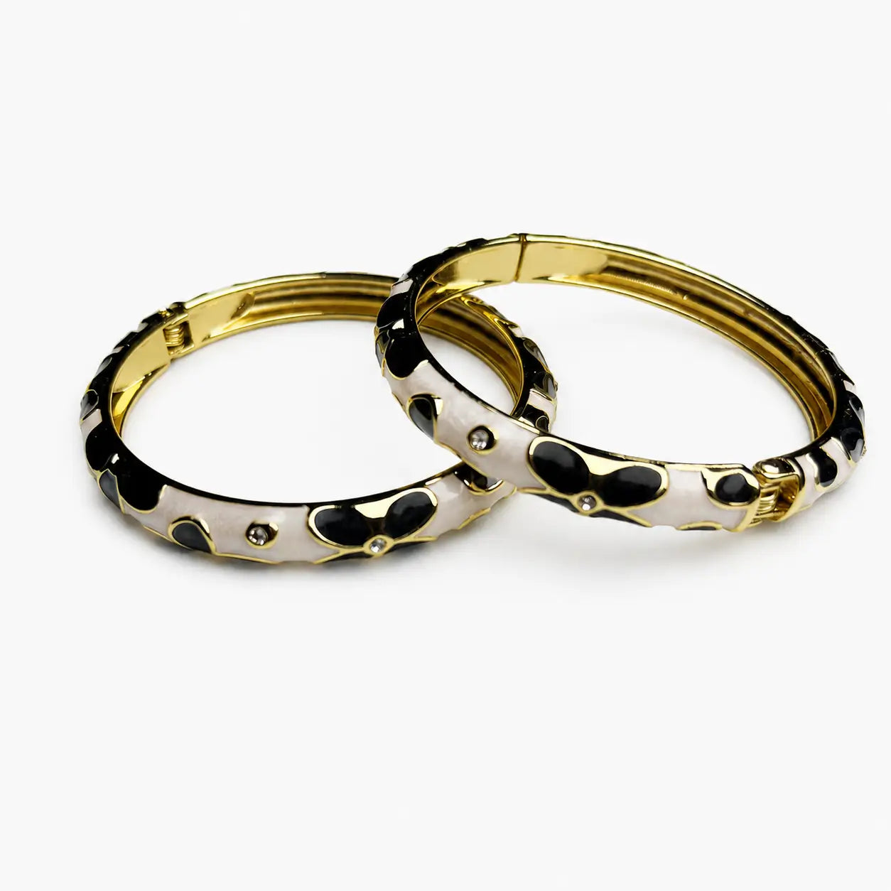 Black And White Abstract Enamel Bangles Pair With Gold-Tone Details On A White Background