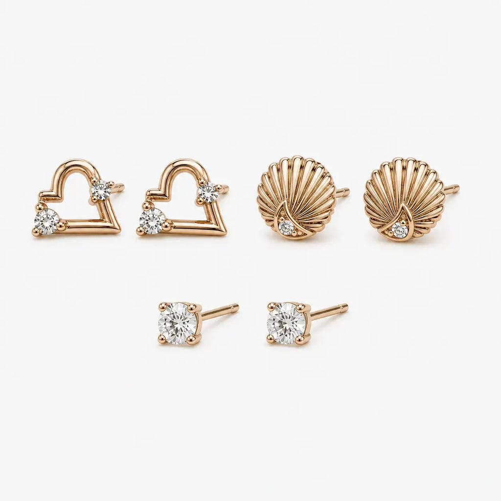 Stud earrings set shown at an angle with rose-gold-colour heart, shell and round clear stone pairs and visible posts.