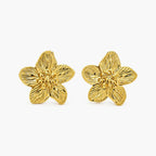 Close-up of textured gold-tone flower stud earrings showing petal detailing