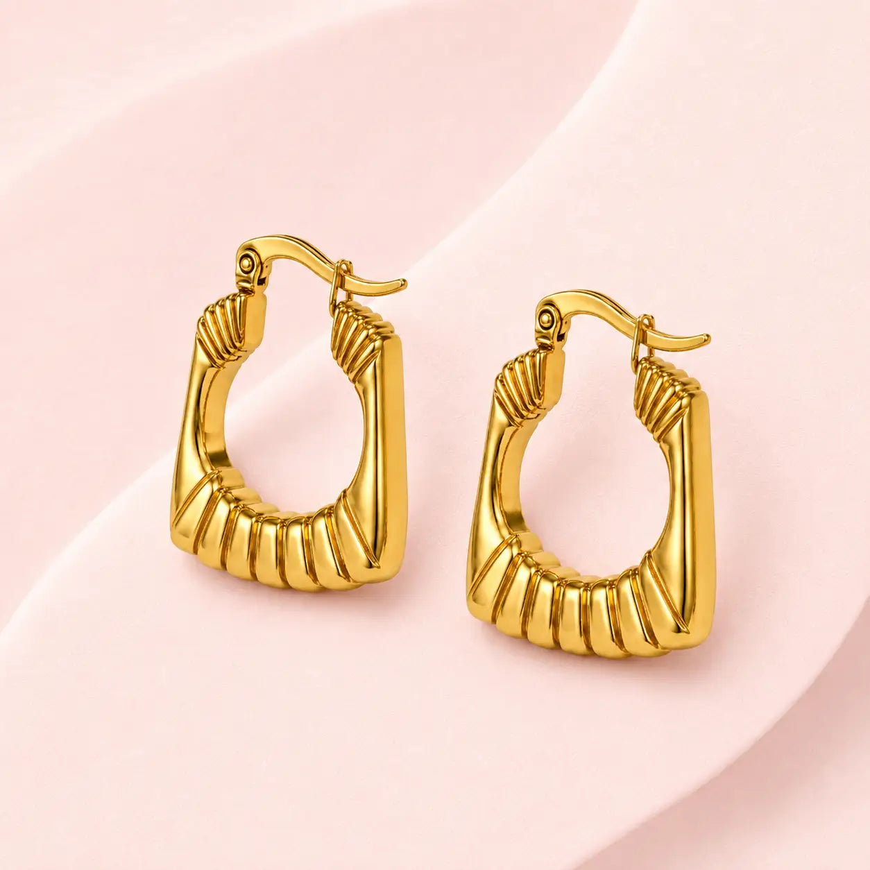 Pair of gold-tone ribbed geometric hoop earrings with hinged closures