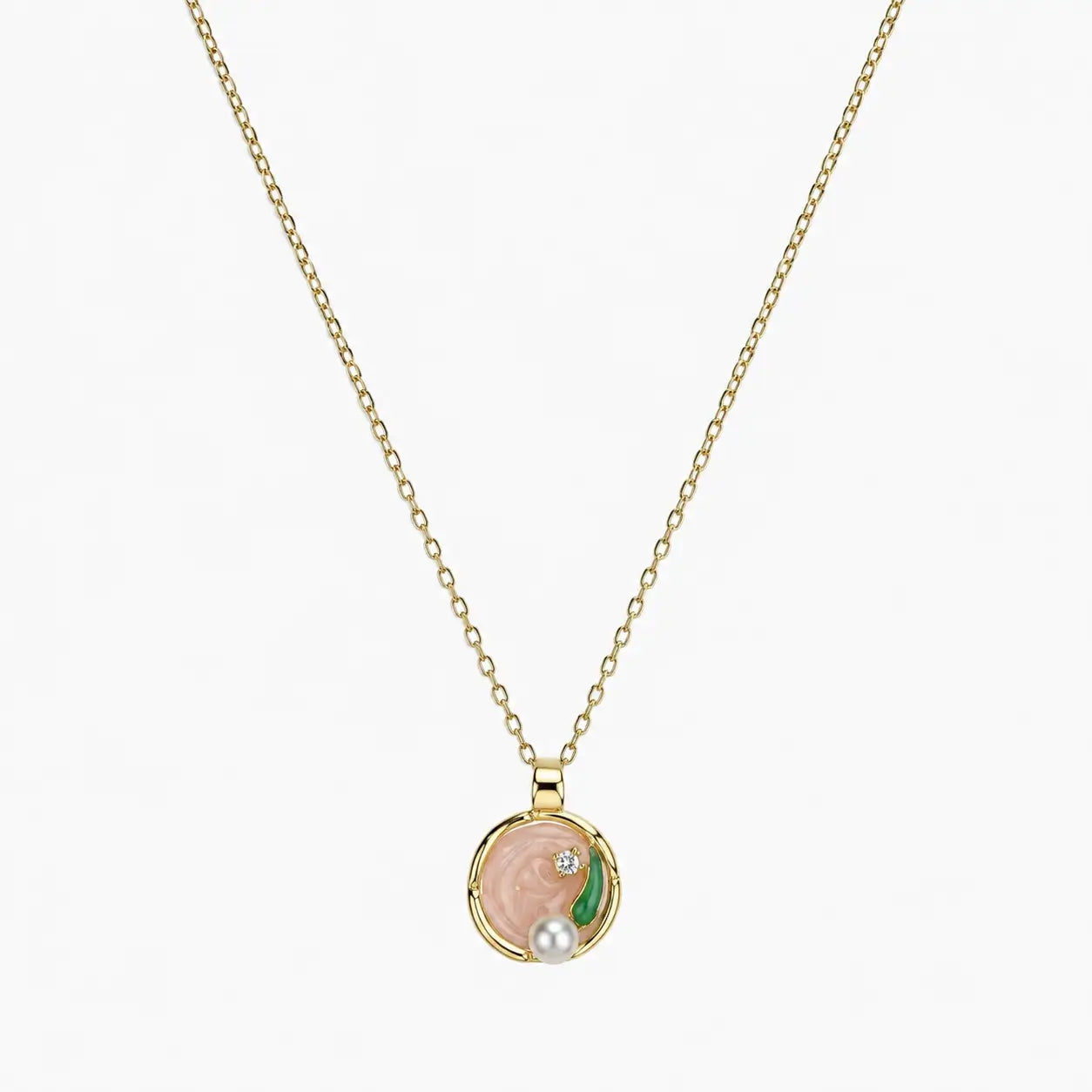 Close-up of a gold-tone pendant necklace with pink swirl centre, green leaf, clear stone and pearl-like accent.