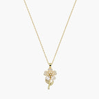 Close-up of a gold-tone pendant necklace with pearlescent flower petals, pearl-like centre and delicate stem.