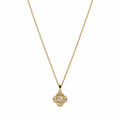  Close-up of a gold-tone pendant necklace with four-lobed clover shape and clear centre stone.