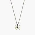 Close-up of a silver-tone pendant necklace for girls with a pearlescent bow and glossy black heart centre.