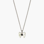 Close-up of a silver-tone pendant necklace for girls with a pearlescent bow and glossy black heart centre.