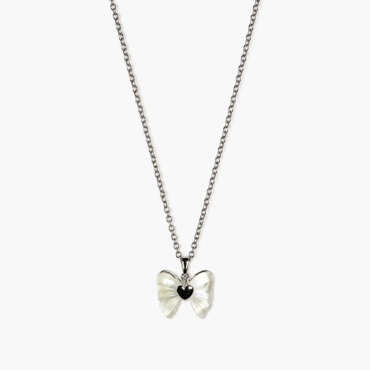 Close-up of a silver-tone pendant necklace for girls with a pearlescent bow and glossy black heart centre.