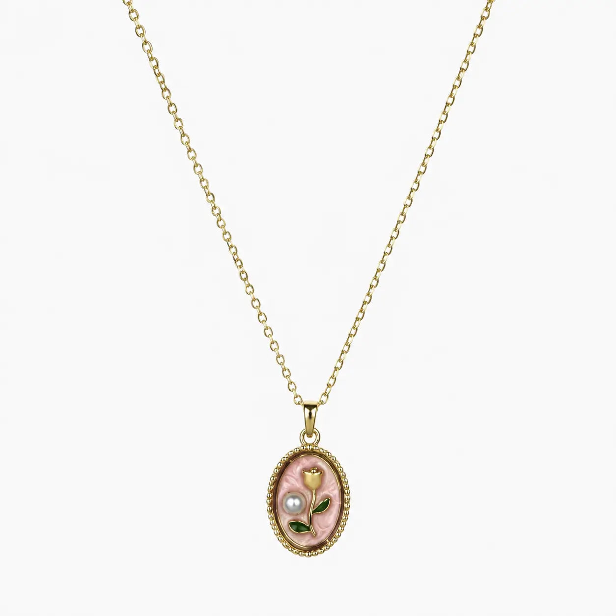 Close-up of a gold-tone pendant necklace with pink oval floral charm, green leaves and pearl-like accent.