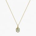 Close-up of a gold-tone pendant necklace with a soft green floral medallion and pearl-like accent.