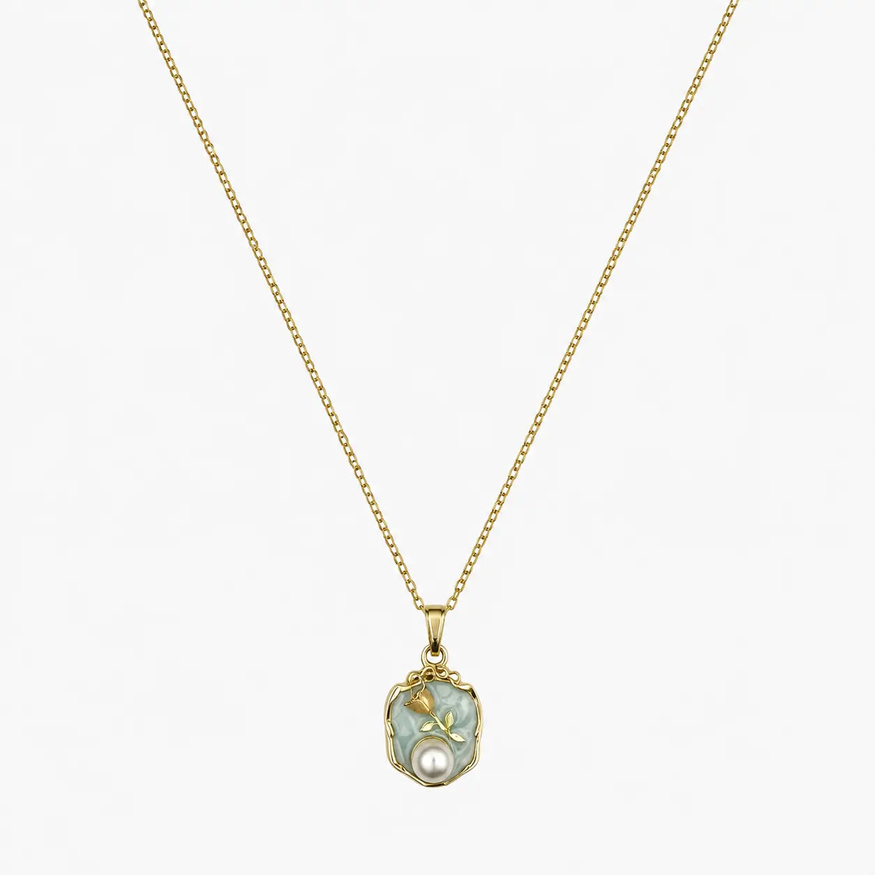 Close-up of a gold-tone pendant necklace with a soft green floral medallion and pearl-like accent.