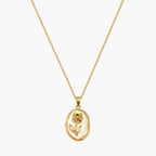 Pendant necklace with gold-tone oval frame, raised rose motif and pearlescent-look white centre, close-up view