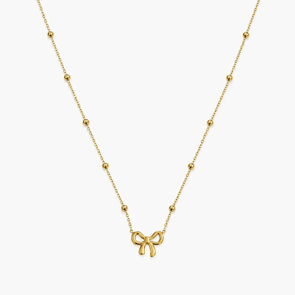 Necklace for girls with gold-tone bow charm and evenly spaced polished bead accents, close-up front view