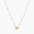 Necklace for girls with gold-tone bow charm and evenly spaced polished bead accents, close-up front view